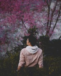 Man standing by purple flower on field