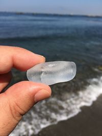 Cropped image of hand holding sea shore