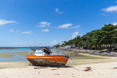 Boat moored on beach against sky