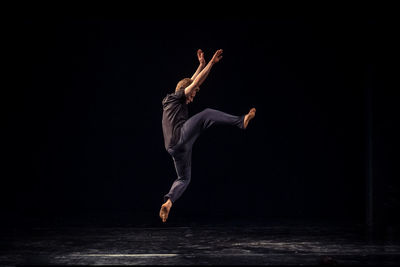 Full length of man jumping against black background