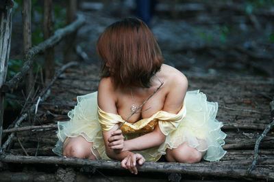 Sensuous woman kneeling on wooden structure