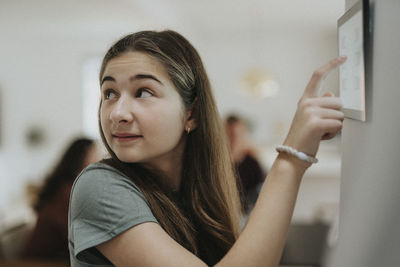 Pre-adolescent girl adjusting room temperature over digital tablet at smart home