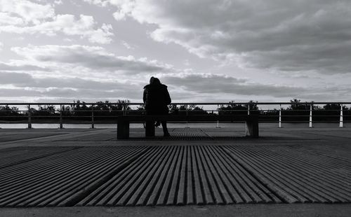 Rear view of man sitting on bench at footpath
