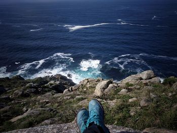 Low section of person on rock by sea