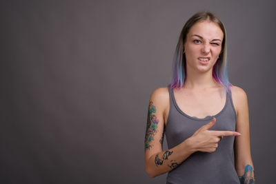 Portrait of woman standing against gray background