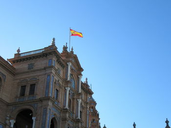 Low angle view of flag against clear blue sky