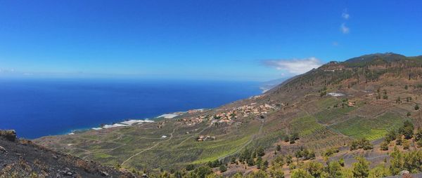 Scenic view of sea and mountains against blue sky