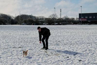 View of teenager playing with his chihuahua in the snow 