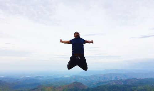 Silhouette of woman jumping against blue sky