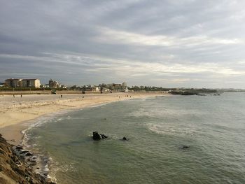 View of calm beach against cloudy sky