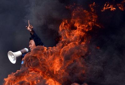 Low angle view of man with fire crackers against gray background