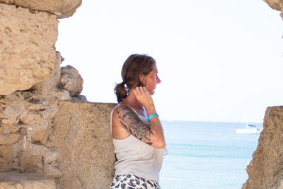 Woman standing by rock against sea and sky