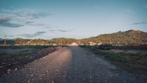 Road leading towards city against sky