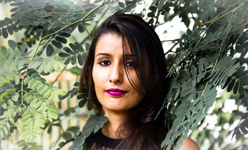 Portrait of beautiful woman standing amidst leaves