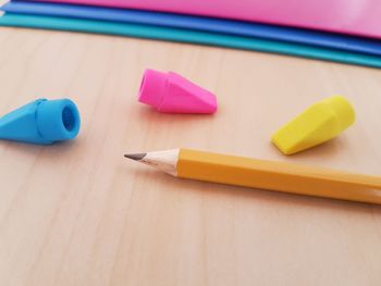 High angle view of pencil with colorful erasers on wooden table