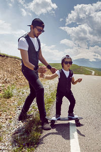 Father teaches son to ride a black skateboard on the road against the backdrop of mount everest 