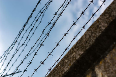 Low angle view of barbed wire fence against sky