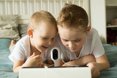 Rear view of boy using mobile phone at home