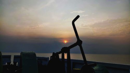 Silhouette tree by sea against sky during sunset