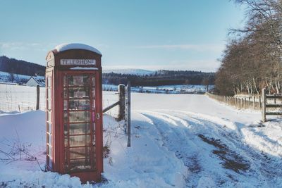Telephone booth on snow covered landscape in winter
