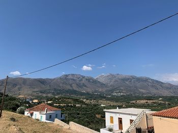Aerial view of townscape and mountains against blue sky