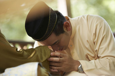 Father and son holding hands while sitting in gazebo at yard