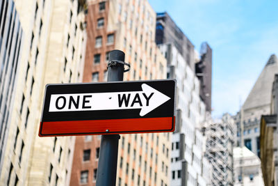 Low angle view of one way sign in city