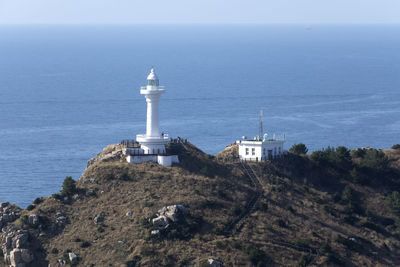 High angle view of lighthouse by sea against clear sky