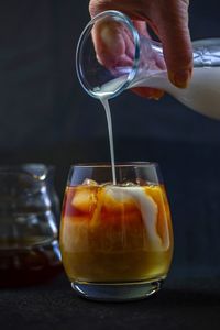 Close-up of hand pouring coffee in glass