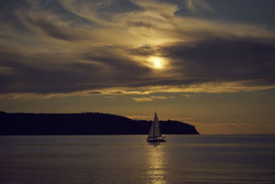Sailboat sailing on sea against sky during sunset