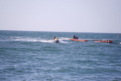 People on boat in sea against clear sky