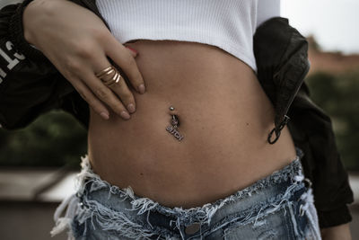 Midsection of woman with pierced belly button outdoors