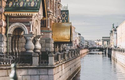 Buildings by canal against sky