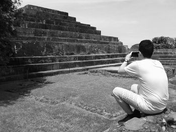Man taking picture of pyramid with mobile phone at archaeological site