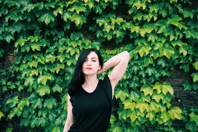 Portrait of young woman standing against plants