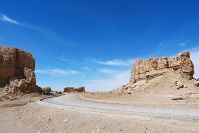 Rock formations on road against sky