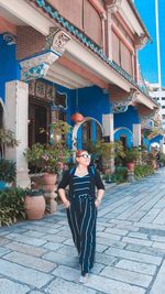 Woman wearing sunglasses walking against built structure