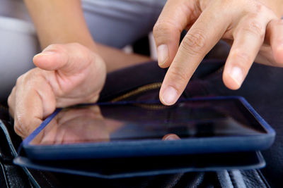 Close-up of woman hand using digital tablet over bag