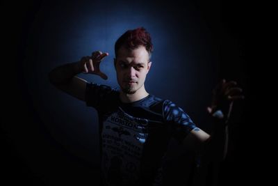 Young man gesturing against black background