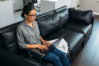 High angle view of woman using laptop while sitting on sofa