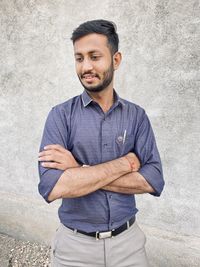 Portrait of young man standing against wall