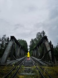 Rear view of person on railroad tracks against sky