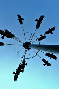 Low angle view of silhouette birds flying against clear sky