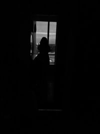 Silhouette woman looking through window