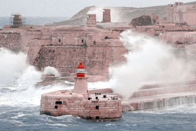 Huge waves crash against the breakwater at the entrance of valletta's grand harbour, malta