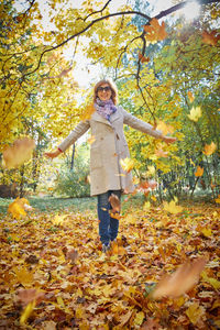 Portrait of smiling woman standing by tree during autumn