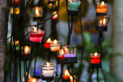 Close-up of lit candles hanging outdoors