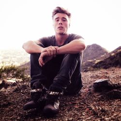 Portrait of young man sitting against clear sky