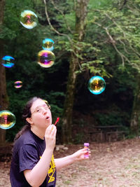 Portrait of woman with bubbles against plants