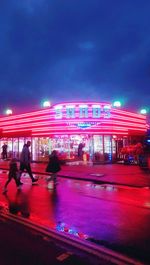 Blurred motion of people on illuminated city street at night